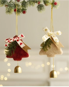 Close-up of plush Christmas tree ornaments with golden bells and festive bows hanging