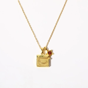 Macro view of gold-plated locket necklace with crescent moon and ruby star charms