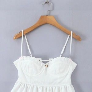 White lace trim camisole dress with pink bow and lace-up front detail on wooden hanger