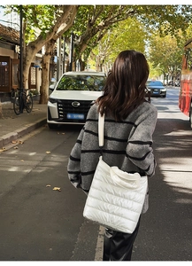 Close-up of white quilted puffer tote bag with wide strap for winter fashion look