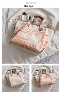 Detail der orangen Beschriftung auf cremefarbenem Canvas-Shopper mit Paspeln