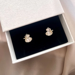 Detail of gold-plated gourd stud earrings with cubic zirconia on black velvet background