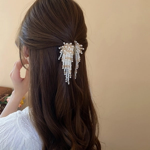 Detail of faux pearl tassel hair claw clip worn on a half-up hairstyle for women
