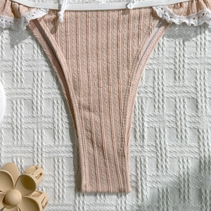 Detail of soft pink ribbed bikini bottom featuring white lace trim and side string ties