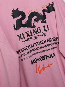 Nahaufnahme von rosa Baumwollstoff mit schwarzer Drachengrafik und Textdruck