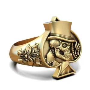 Détail d'une bague tête de mort dorée vintage avec cadre as de pique et gravure