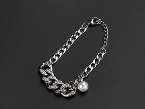 Detailed macro view of silver Cuban chain bracelet with pavé zircons and white pearl pendant