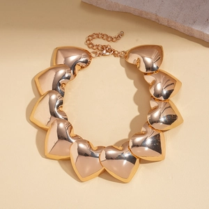 Close-up of chunky gold metallic heart link necklace with polished surface on stone prop