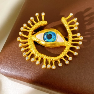 Macro shot of vintage eye brooch with gold hammer texture, blue enamel and rhinestones