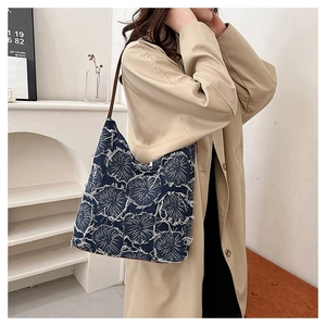 Detail showing vintage denim tote bag with frayed floral patterns on beige trench coat