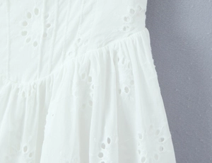 Gros plan détaillé de la robe blanche avec broderie anglaise et texture en coton plissé