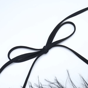 Détail de robe noire avec fines lanières à nouer et garniture en plumes d'autruche chic