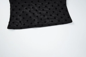 Détail de maille noire transparente à pois floqués avec couture d'ourlet soignée
