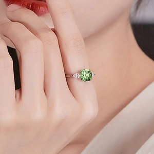 Vista detallada de un anillo de plata con piedra preciosa cuadrada verde en un dedo mujer