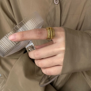 Detailed close-up of a layered gold ring worn on the finger against a warm background