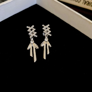 Macro shot of silver bow earrings with sparkling rhinestones and long metallic tassels