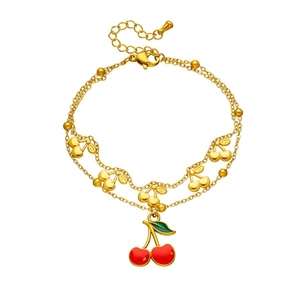 Gros plan d'un bracelet double doré avec des cerises en émail rouge et fermoir OT