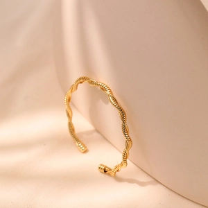 Macro shot of gold twisted rope bangle showing the elegant wavy texture and metallic finish