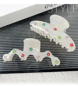 Detail of pearlescent white hair claws with colorful rhinestone flower patterns