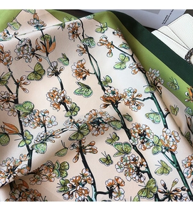 Detailed macro view of the floral silk scarf showing green border and butterfly print