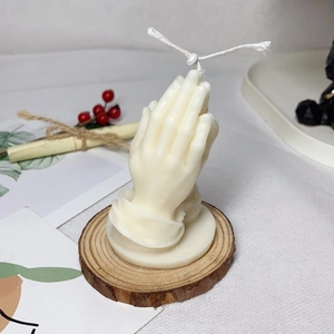 Artistic praying hands scented candle in ivory white on a rustic wood base