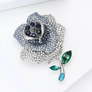 Détail d'une broche rose avec cristaux bleus et feuilles vertes sur base argentée