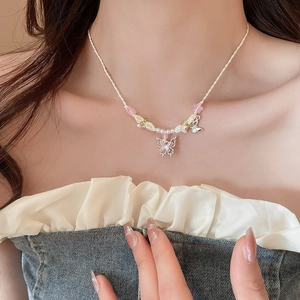 Détail du pendentif papillon argenté et des perles colorées sur collier en corde blanche