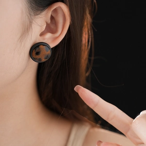 Gros plan d'une boucle d'oreille léopard avec bord noir portée par un mannequin