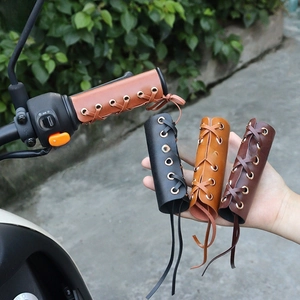 Detail view of vintage leather handlebar covers with cross-laced design in four colors