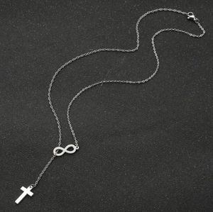 Minimalist stainless steel infinity and cross double pendant necklace on a black surface