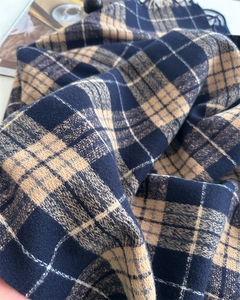 Détail d'une écharpe en cachemire à carreaux marine et camel avec texture douce