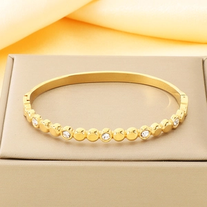 Détail d'un bracelet en acier titane doré avec cinq zircons étincelants arrondis