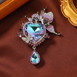 Elegant butterfly brooch with purple crystal heart and droplet pendant on silk fabric