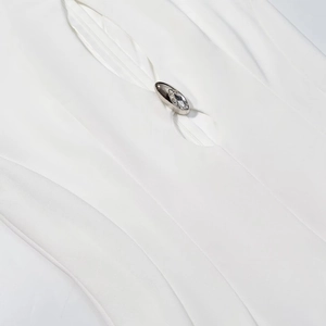Detail of white dress fabric with silver metal buckle and faceted crystal stone