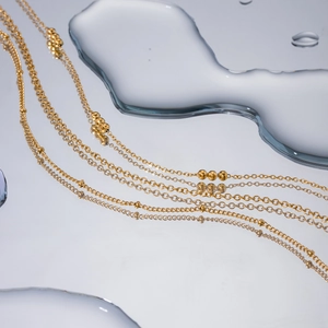 Collier à trois rangs en acier inoxydable doré 18k sur fond mouillé réfléchissant