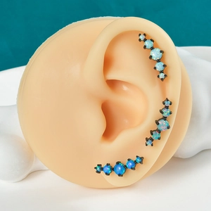 Detailed view of black plated barbell earrings with iridescent opal stones on ear model