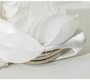 Detailed macro view of white fabric petals and silver metal clasp on an elegant evening bag