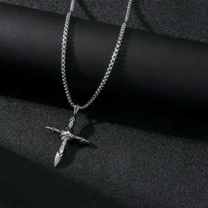 Vue détaillée d'un pendentif croix en acier inoxydable argenté avec gravure gothique fine