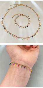 Detail view of gold necklace and bracelet set with colorful enamel drop pendants