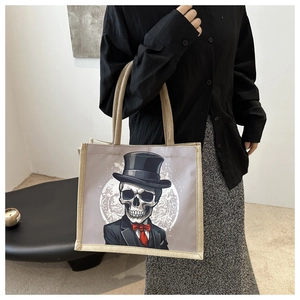 Détail du sac cabas en toile avec imprimé de crâne de gentleman et nœud papillon rouge