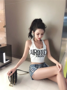 Dettaglio del crop top bianco a costine con scritte e pantaloncini di denim blu strappati