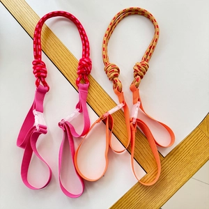Close-up of pink and orange nylon pet leashes with plastic buckles on a wooden table