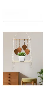 Détail de l'étagère en macramé avec plateau en bois et pompons feuilles tissés marron