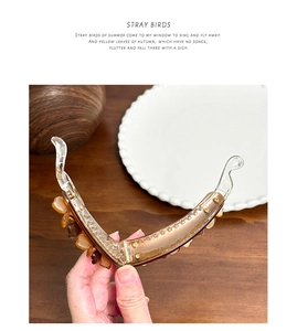 Detailed amber resin banana hair clip showing its open mechanism and translucent texture