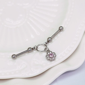 Detail eines Industrial-Barbells aus Chirurgenstahl mit rosa Zirkonia-Blüte