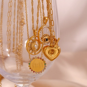 Detail of 18K gold plated evil eye and heart charms on a pink silk fabric background