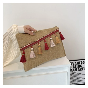 Detail of straw envelope clutch featuring colorful woven band and ethnic tassel fringe