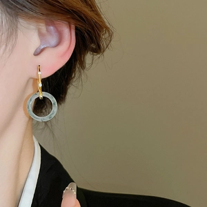 Détail de boucles d'oreilles en or bambou avec anneau de jade en résine et zircons