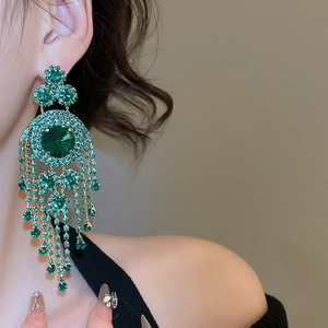Detailed close-up of long emerald green tassel earrings with sparkling rhinestones