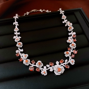 Detail of silver rose necklace with orange gemstones on a black jewelry tray